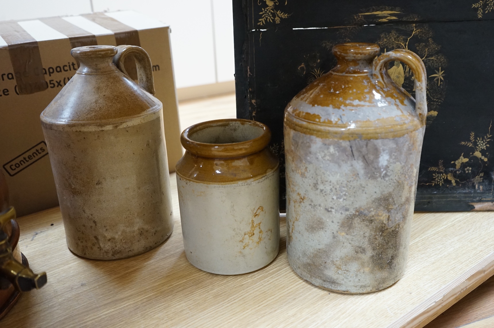 Three graduated copper haystack measures, H 39cm x W 40cm (inc spout), H 35cm x 25cm and H25cm x 18cm, Three stoneware jars H 32cm x W 20cm (two jars), H 20cm x W 16cm (1 jar)